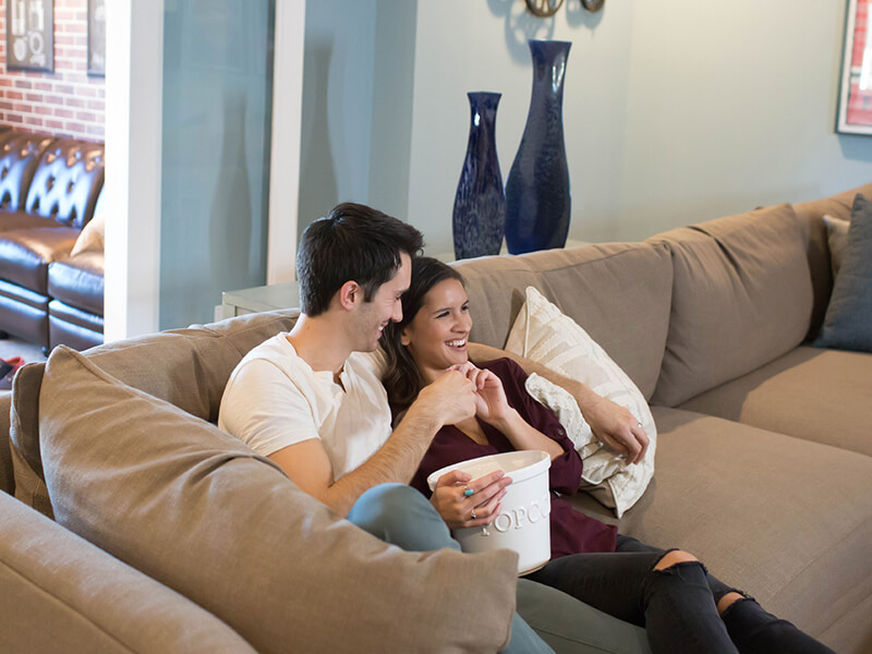 Couple watches movie on sofa with popcorn