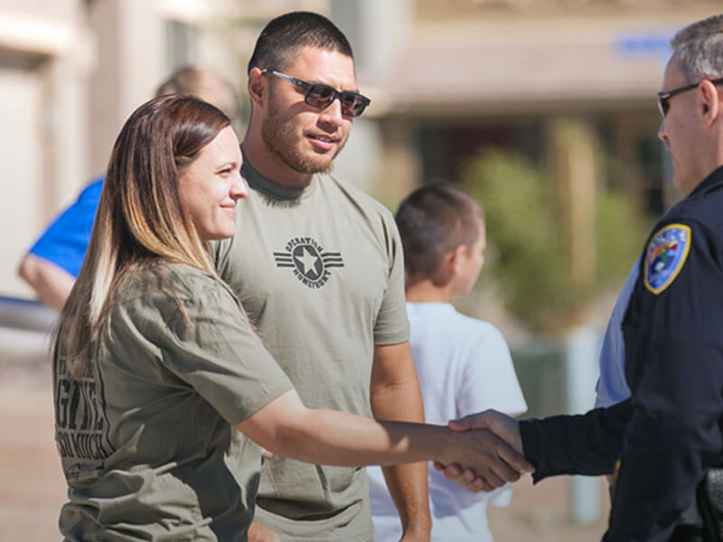 Police officer shaking hands with some troops