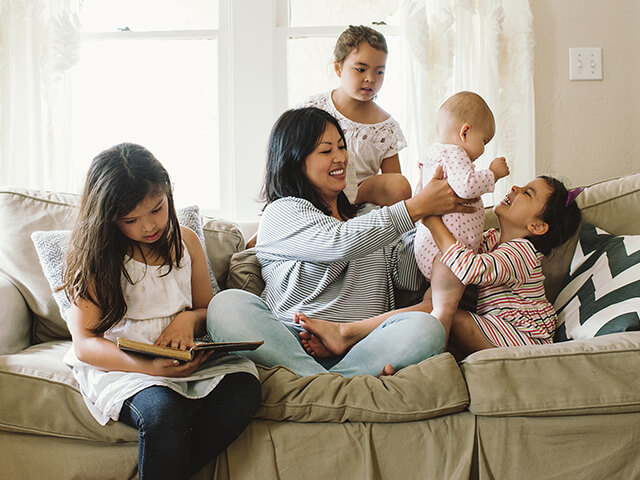 Family hanging out on the couch, holding a baby